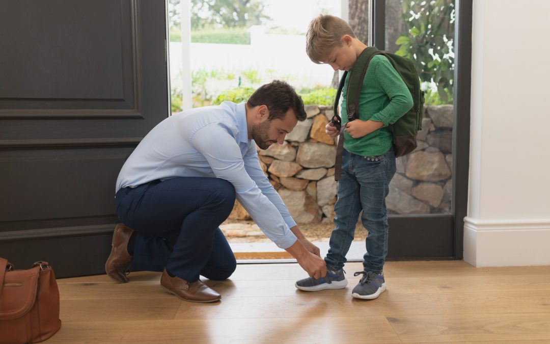 Father Tying Son's Shoes Before Visiting Family Podiatrist