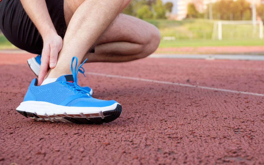 Male Athlete on Track Rubbing Painful Ankles and Prepping for Laser Treatment
